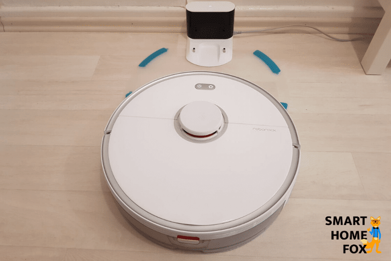 Roboter Staubsauger mit Wischfunktion steht an der Ladestation auf einer Kunststoffmatte
